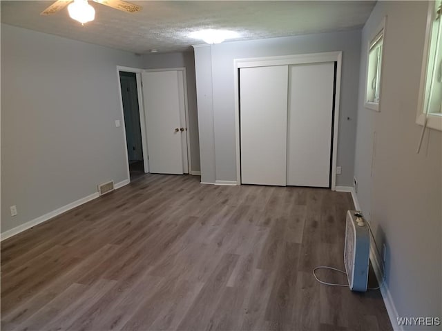 unfurnished bedroom featuring ceiling fan, wood-type flooring, a closet, and a textured ceiling