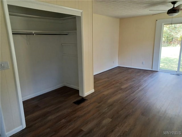 unfurnished bedroom with a closet, dark hardwood / wood-style floors, and ceiling fan