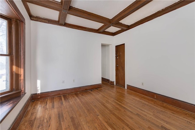 empty room featuring wood-type flooring, coffered ceiling, and beam ceiling