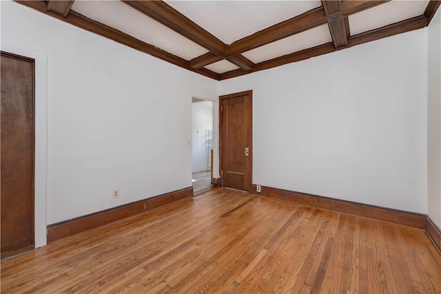 empty room featuring light wood-type flooring, beam ceiling, and coffered ceiling