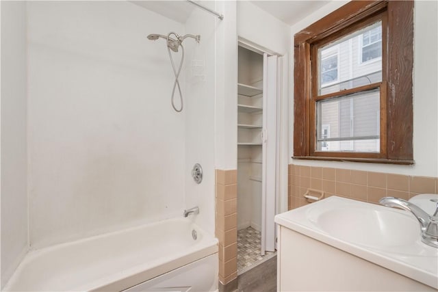 bathroom featuring shower / washtub combination, vanity, and tile walls