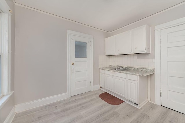 kitchen with crown molding, light hardwood / wood-style flooring, sink, white cabinets, and decorative backsplash