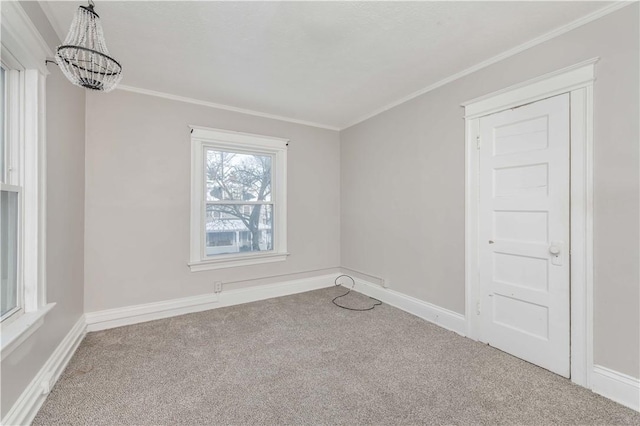 empty room featuring carpet floors, crown molding, and a notable chandelier