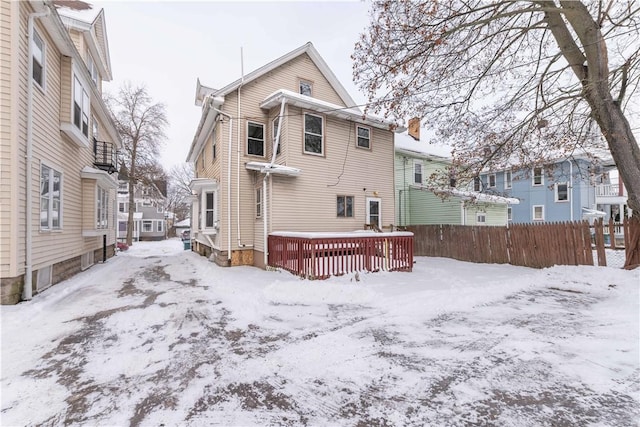 snow covered rear of property with a wooden deck