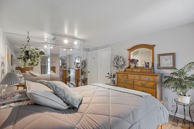 bedroom featuring rail lighting and wood-type flooring