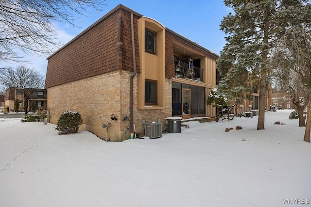 snow covered property featuring a balcony and central AC unit