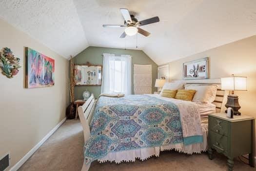 carpeted bedroom with ceiling fan, a textured ceiling, and vaulted ceiling