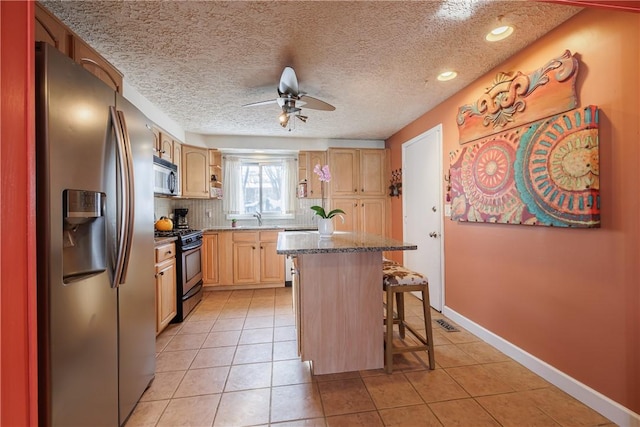 kitchen with a kitchen breakfast bar, stainless steel appliances, a center island, light tile patterned flooring, and light brown cabinetry