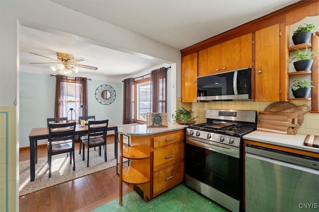 kitchen with ceiling fan, tasteful backsplash, hardwood / wood-style flooring, kitchen peninsula, and stainless steel appliances