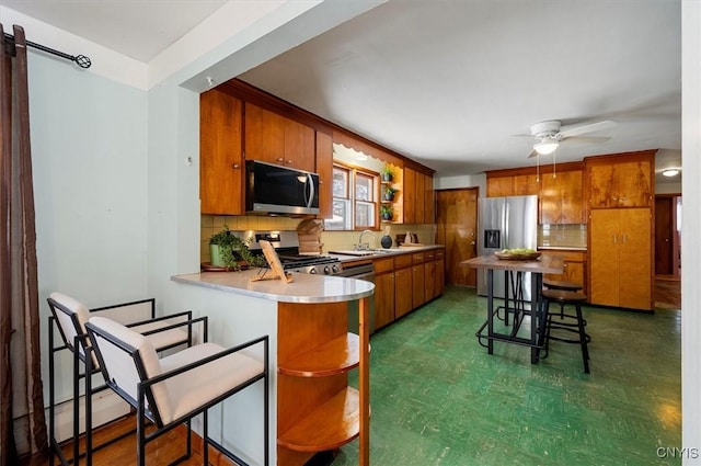 kitchen with appliances with stainless steel finishes, tasteful backsplash, sink, kitchen peninsula, and ceiling fan