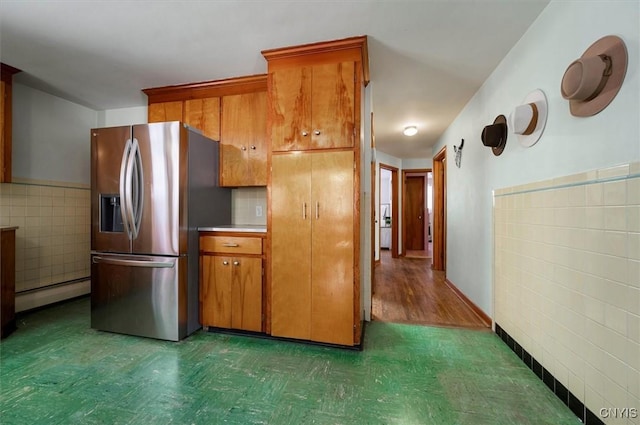 kitchen featuring a baseboard heating unit, tile walls, and stainless steel fridge