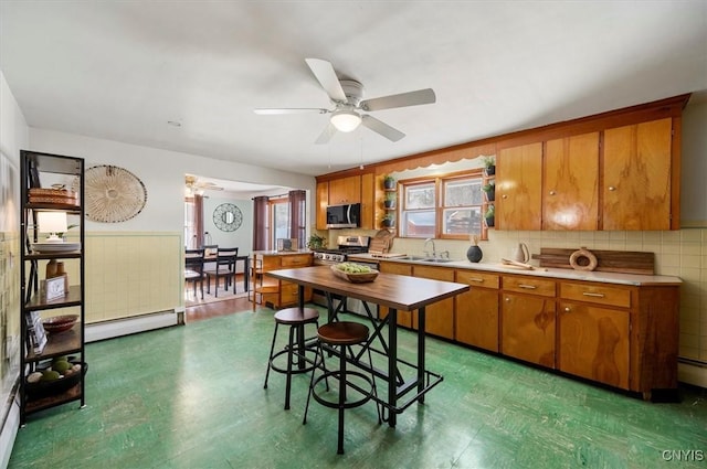 kitchen with sink, ceiling fan, baseboard heating, and appliances with stainless steel finishes