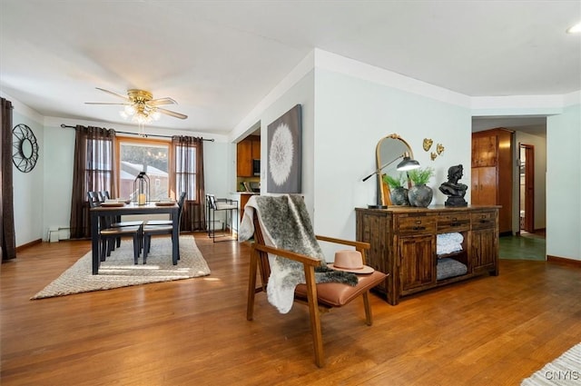 living area featuring ceiling fan, a baseboard radiator, and wood-type flooring