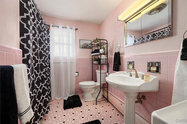 bathroom with tile patterned floors, tile walls, and toilet