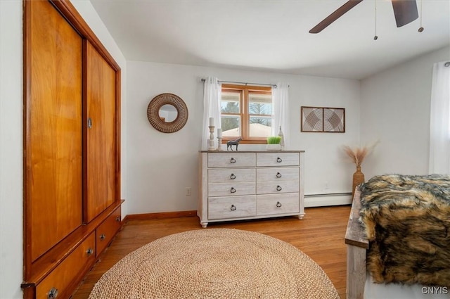 bedroom featuring a baseboard radiator, light hardwood / wood-style floors, a closet, and ceiling fan