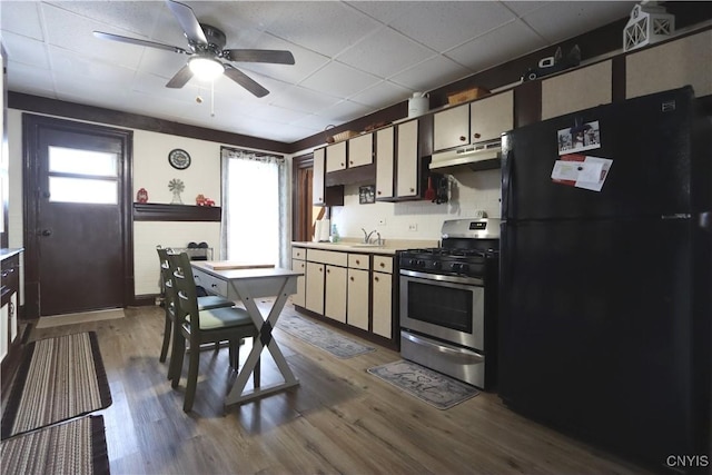 kitchen featuring wood-type flooring, black fridge, ceiling fan, and stainless steel gas stove