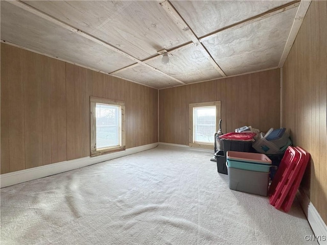 additional living space with ceiling fan, light carpet, and wood walls