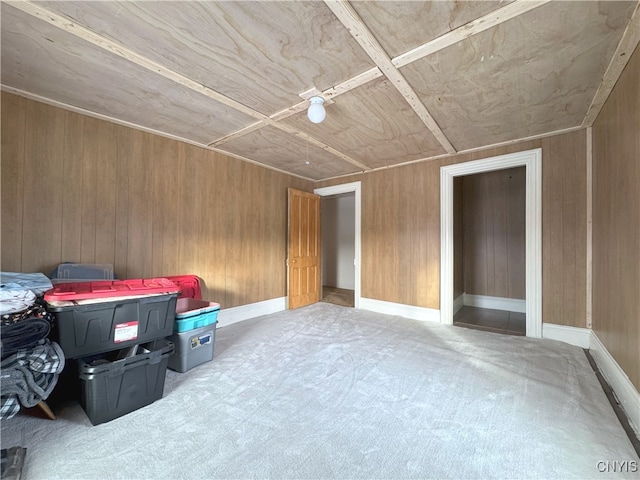 unfurnished bedroom featuring light colored carpet and wood walls