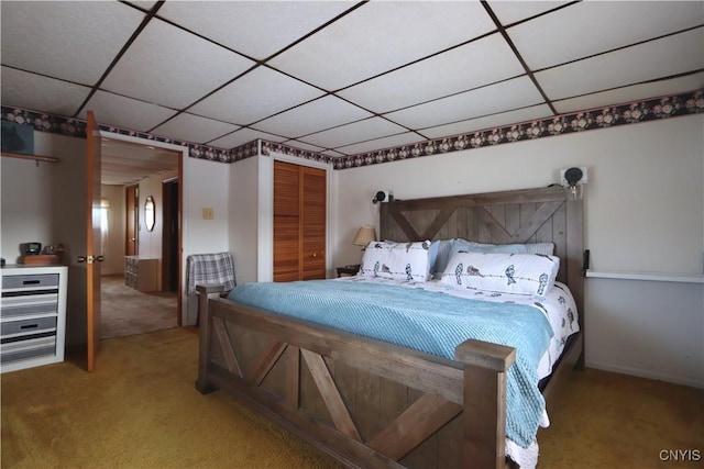 carpeted bedroom featuring a paneled ceiling and a closet