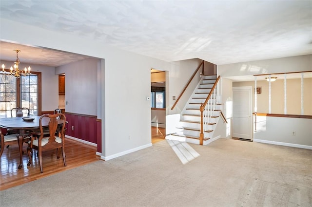 interior space featuring baseboard heating, light carpet, and a notable chandelier