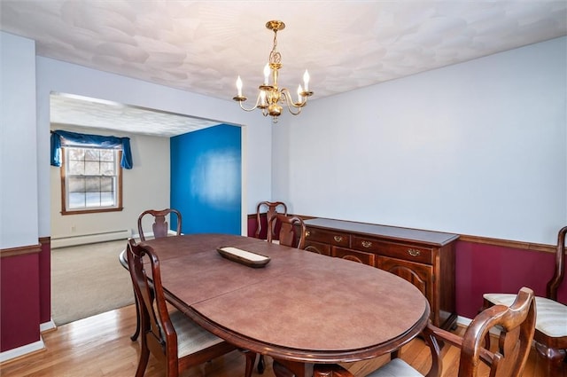 dining room with baseboard heating, an inviting chandelier, and light hardwood / wood-style flooring