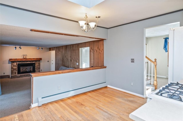 kitchen featuring a baseboard heating unit, an inviting chandelier, light hardwood / wood-style floors, ornamental molding, and a brick fireplace