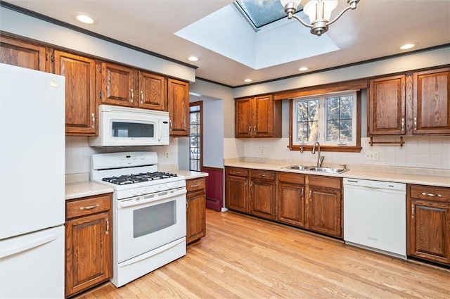 kitchen featuring white appliances, a chandelier, sink, light hardwood / wood-style flooring, and backsplash