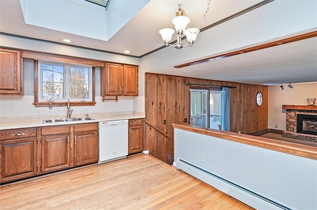 kitchen with white dishwasher, a fireplace, a baseboard radiator, sink, and pendant lighting