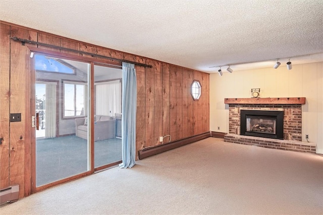 unfurnished living room featuring rail lighting, a baseboard radiator, a textured ceiling, and wood walls