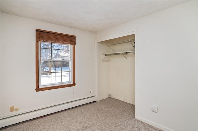 unfurnished bedroom featuring baseboard heating, light colored carpet, and a closet