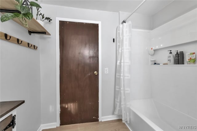 bathroom with wood-type flooring and shower / bath combo with shower curtain