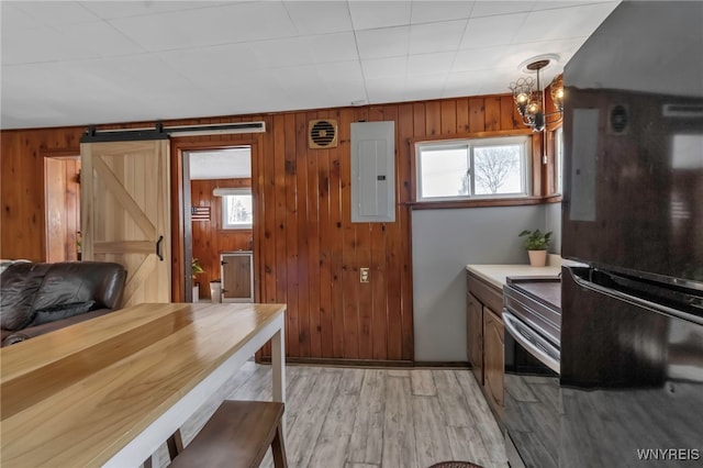 kitchen featuring hanging light fixtures, electric panel, a barn door, black fridge, and stainless steel electric range