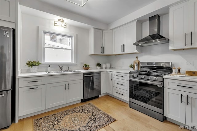 kitchen with white cabinets, appliances with stainless steel finishes, light hardwood / wood-style flooring, and wall chimney exhaust hood