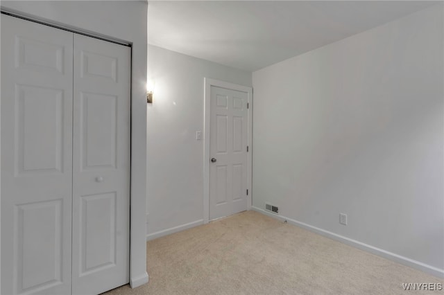 unfurnished bedroom with a closet and light colored carpet