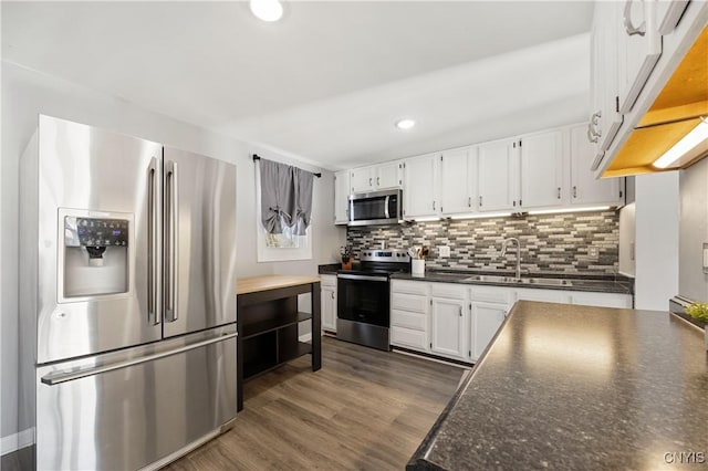 kitchen with white cabinets, dark hardwood / wood-style flooring, stainless steel appliances, tasteful backsplash, and sink