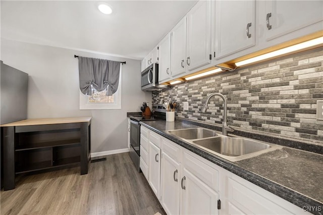 kitchen featuring wood-type flooring, sink, backsplash, white cabinets, and stainless steel appliances