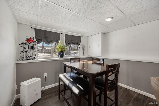 dining space with a paneled ceiling and dark hardwood / wood-style flooring