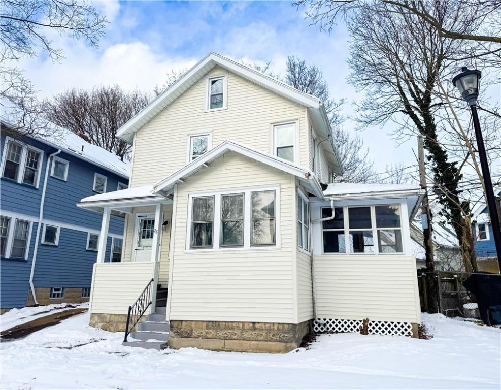 snow covered back of property with a sunroom