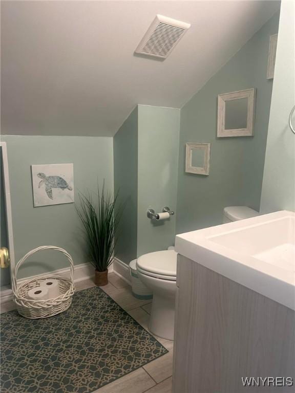 bathroom featuring vanity, toilet, and lofted ceiling