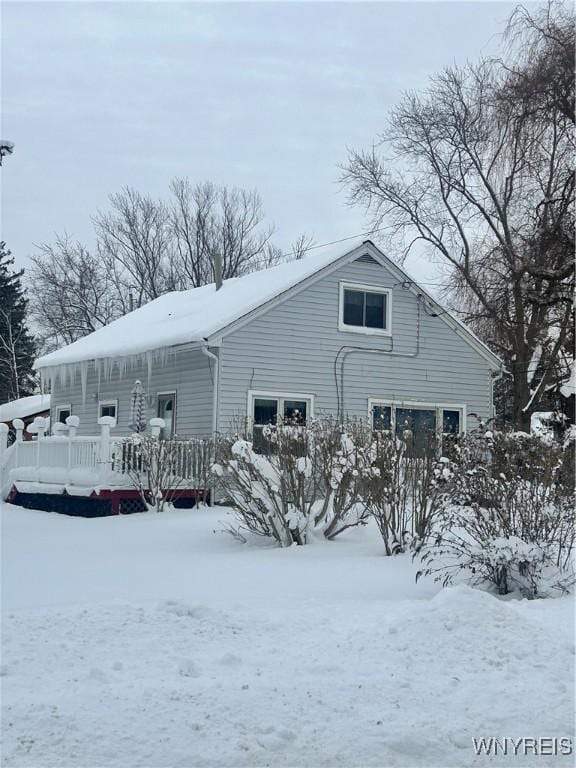 snow covered back of property with a porch