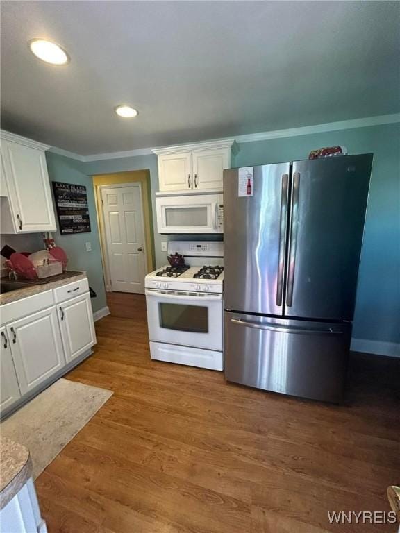 kitchen with white cabinetry, white appliances, dark hardwood / wood-style floors, and crown molding