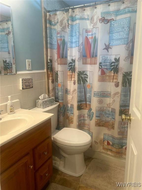 bathroom with vanity, toilet, tile walls, and backsplash