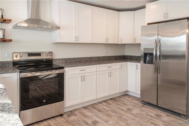 kitchen featuring white cabinetry, wall chimney exhaust hood, light wood-type flooring, and appliances with stainless steel finishes