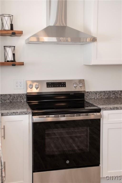 kitchen with open shelves, stainless steel electric stove, wall chimney exhaust hood, and white cabinets