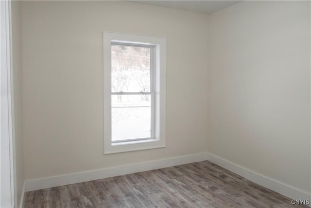 unfurnished room with wood finished floors, baseboards, and a wealth of natural light