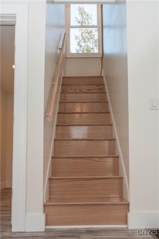 staircase with baseboards and wood finished floors