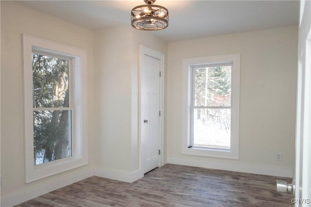 interior space featuring a notable chandelier, wood finished floors, and baseboards