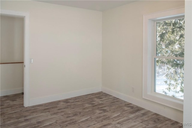 empty room with plenty of natural light, baseboards, and wood finished floors