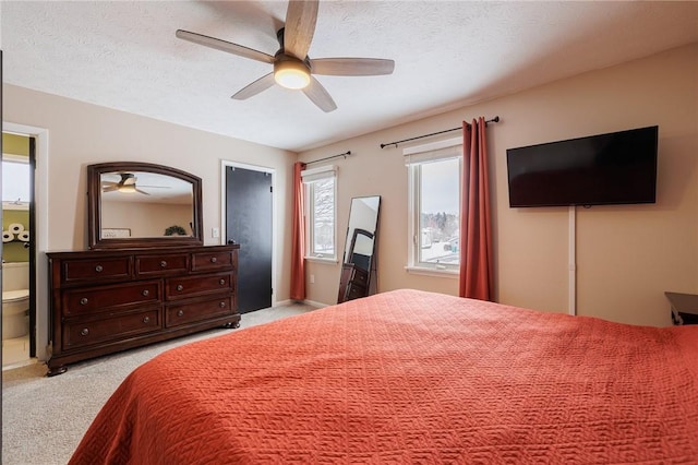 bedroom with ceiling fan, light colored carpet, a textured ceiling, and ensuite bathroom