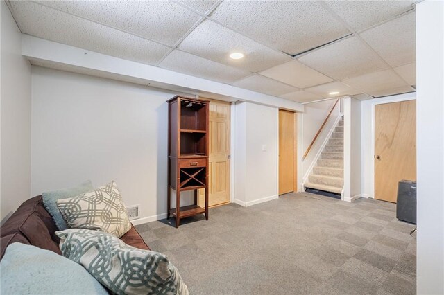 sitting room featuring carpet and a drop ceiling